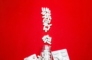 Exclamation mark made by pills, isolated on red background. Flat lay. Top view and copy space