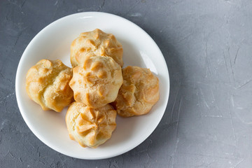 Homemade pastries: profiteroles with butter cream on a white plate.