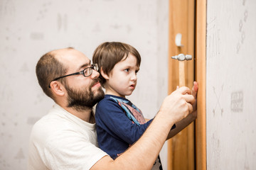 Serious father and son hammering nail in wooden plank, family leisure, support