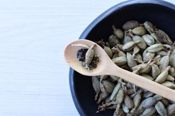 Dry cardamom seed (Elettaria cardamomum) displayed in containers and spoons