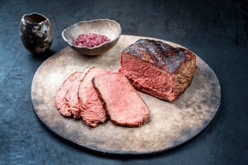 Traditional Commonwealth Sunday roast with sliced cold cuts roast beef with red salt as closeup on a modern design plate