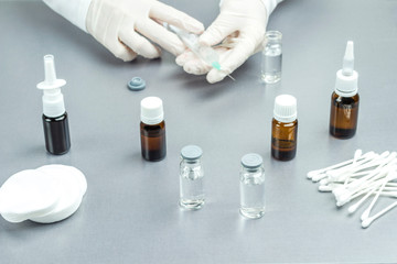 Hands in medical gloves hold a syringe. Glass Bottle with medicines