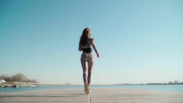 girl athlete with a beautiful figure runs on the pier of the lake. Slow motion