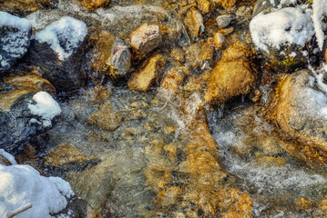 close up of flowing clear water on rocks in a stream in the forest