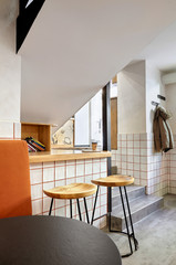 Fototapeta na wymiar Stylish. Modern interior of cafe.Authentic style with element of loft.Round black and white tables,chairs and orange sofa..White tiles with orange lines.Orange,white and grey colors.