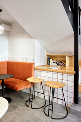 Stylish. Modern interior of cafe.Authentic style with element of loft.Round black and white tables,chairs and orange sofa..White tiles with orange lines.Orange,white and grey colors.
