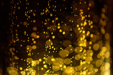 Beer bubbles in the glass on black background. Golden bubbles rising in fluid. Abstract macro background. Blurry and defocused.