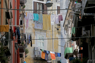 Fototapeta na wymiar Laundry hangs from clothes lines strung over a narrow street in Naples, Italy.