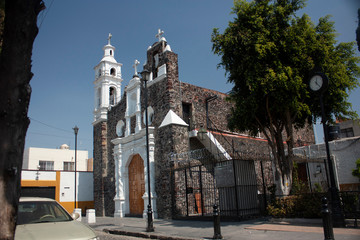 Fototapeta premium 18th century white painted church in Mexico City between the two-color streets that adorn with the yellow-white facades that give a rustic rustic touch to the magical town of the Assumption
