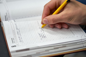 Close-up photo of a hand with a pen of a businessman who writes in a notebook in Russian.