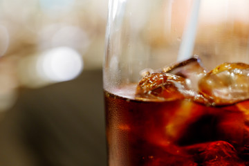 Close up and macro view of cola and ice cube with steam on glass, and blur abstract background of bokeh.