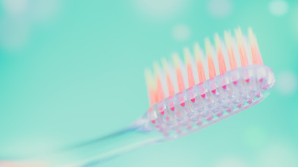 Orange plastic toothbrush on a green background with bubbles.