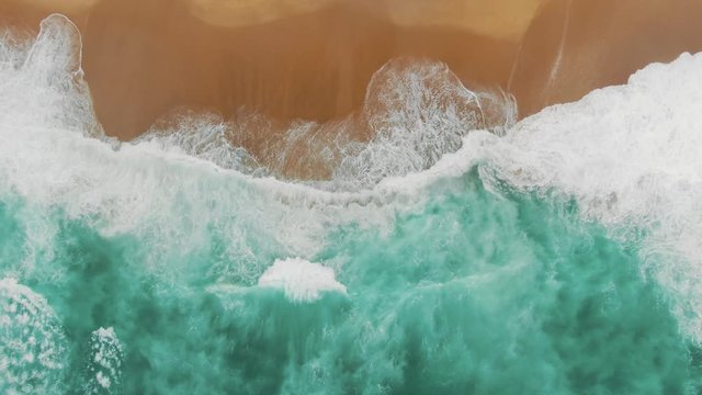 aerial view of immense turquoise ocean waves washing beach