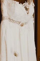 Detail of a white wedding dress hanging.