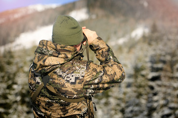 Hunter man in Masking Camouflage Uniform with Binoculars.