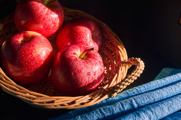 red apples in hand made basket with blue background