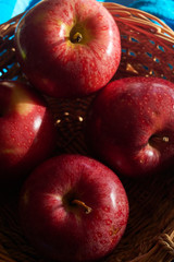 red apples in hand made basket with blue background