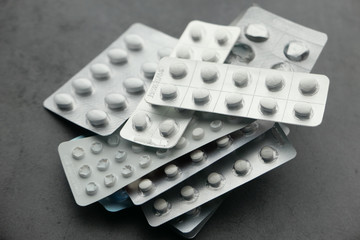 close up of stack of white pills on black background 