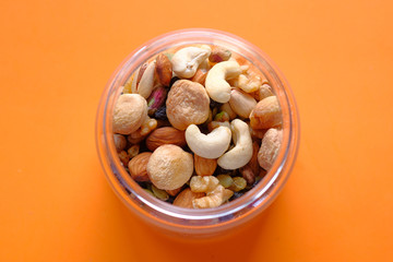 top view of mixed nut in a jar on orange background 