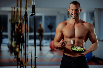 healthy young man eating vegetables green salad at gym - 328411565