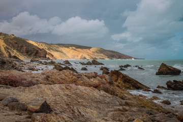 Stunning coastal cliffs in Jericoacoara, Ceará, Brazil, with rocks in the foreground, clear skies, and impressive geological formations in the background on a sunny day