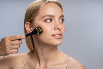 Fototapeta premium Beautiful relaxed girl using a face massager