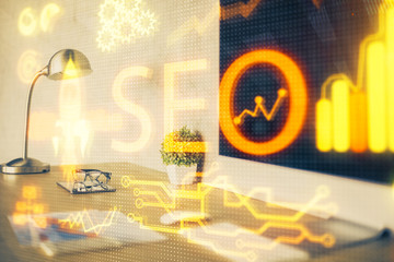 Double exposure of table with computer and seo drawing hologram. Search optimization concept.