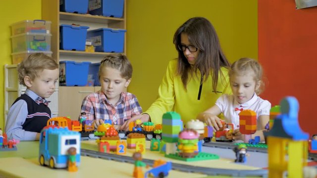 Children in the classroom make figures with teacher. Modern technology concept