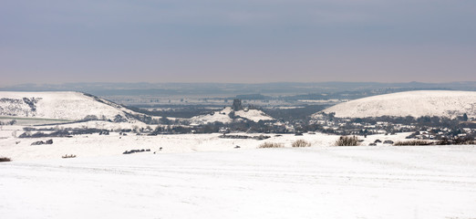 Ruins of Corfe Castle viewed across snow-covered fields