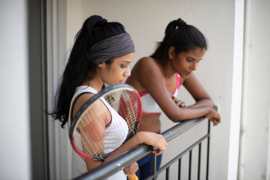 Indian black and white brunettes girls with a tennis bat enjoying themselves in sportswear on a balcony in a white background. Indian lifestyle - Powered by Adobe