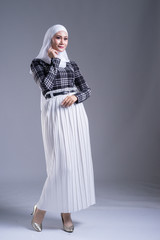 Naklejka premium Full length portrait of a beautiful Muslim female model in a hijab and casual wear on grey background. Hijab and Muslim fashion lifestyle concept