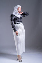Full length portrait of a beautiful Muslim female model in a hijab and casual wear on grey background. Hijab and Muslim fashion lifestyle concept