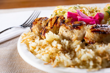 A closeup view of a chicken shish kabob combo plate in a restaurant or kitchen setting.