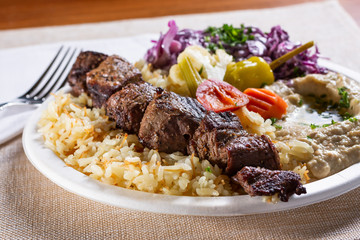 A view of a beef kabob combo plate, in a restaurant or kitchen setting.