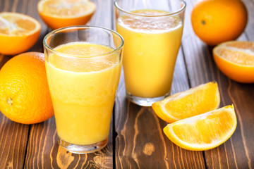 Two glass of fresh orange juice with fresh fruits on wooden table. Healthy drink and food.
