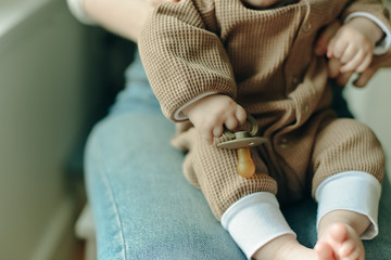 baby holds a pacifier in his mother arms