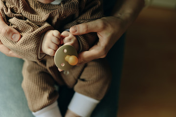 baby holds a pacifier in his mother arms