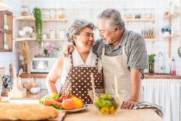 Couple senior Asian elder happy living in home kitchen. Grandfather cooking salad dish with...