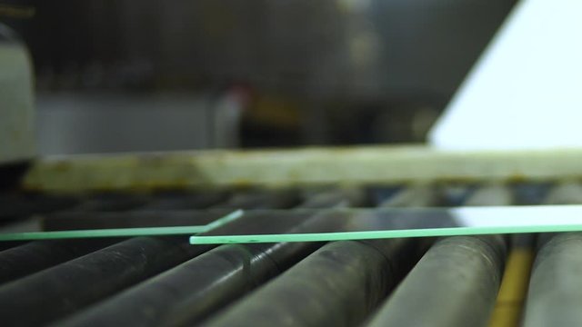 Human hand taking glass pane from Band Conveyor Line in factory,close up