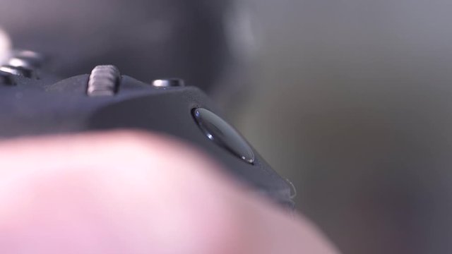 Close up/macro footage of a photographer's  finger pushing the button on a DSLR Camera and adjusting settings before taking photographs.