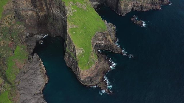 Sea cliffs landscape on Faroe Islands coastline, aerial tilt reveal
