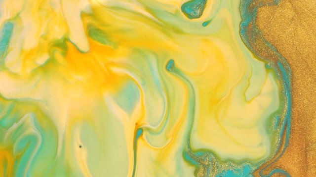 Light blue and gold liquid glitter paint mix. Abstract background. A real beautiful substance flows. Motion mixed colorful ink macro 