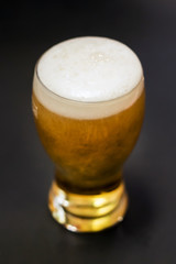 Pouring beer into a tall glass isolated on black background