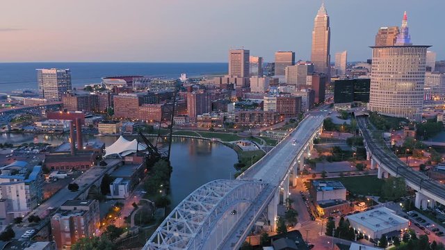 Aerial flying over downtown Cleveland, Cuyahoga river & the Flats at sunset, Ohio, USA