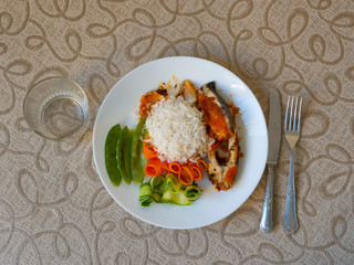 healthy eating: table with dish containing fish fillet, carrots, green beans, salad and a glass of red wine. Seen from above