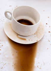 The coffee spilled out of a sloppy, messy glass onto a white surface.