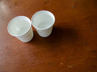 Two paper cups of water on wooden table background, Close up and macro shot
