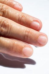 Woman's wet left hand with water drops on middle finger,  White acrylic background, Close up & Macro shot, Selective focus, Asian Body skin part, Relaxing Bath, Healthcare concept