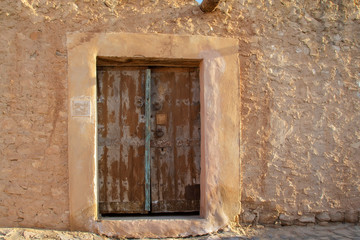 North African-style wooden door to the wall of a ruined stone