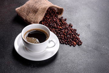 A cup of fresh scented morning coffee for a cheerful start to the day. Beautiful coffee cup with coffee on a dark table